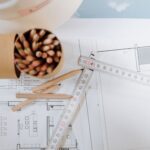 Colorful pencils and ruler atop architectural blueprints on a workspace.